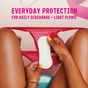 A person with yellow painted nails holds a pink pair of underwear with a Flo Organic Bamboo Panty Liner by Here We Flo inside. The text above reads, Everyday protection for daily discharge + light flows.