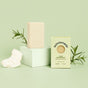 A bar of Sunniemade Moisturizing Hand & Body Bar Soap - Very Rosemary, its box labeled with the brand name, rests alongside rosemary sprigs on a light green background—a fresh and inviting display of natural body care.