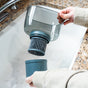 A person holds the Epic Water Filters USA Nano XP Water Filter Pitcher | Reduces Bacteria & PFAS in gray over a sink, removing the bottom section to reveal its advanced black cylindrical filter, with a granite countertop in the background.