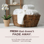 A wicker basket with neatly rolled white towels sits on a table beside a potted white orchid. Text reads: FRESH that ENDURES. Experience up to 30 days of gentle scent with Mrs. Meyer’s FreshBloom™ Baby Laundry Detergent, crafted with naturally derived ingredients. Specially made for your nursery, this detergent keeps baby clothes clean and delicately fresh wash after wash.