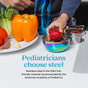 A child places a strawberry into an Ahimsa Simple Serve Bowl beside vibrant veggies. Text: “Pediatricians choose non-toxic Ahimsa Simple Serve Bowls—stainless steel is the ONLY kid-friendly material recommended by the AAP.”.