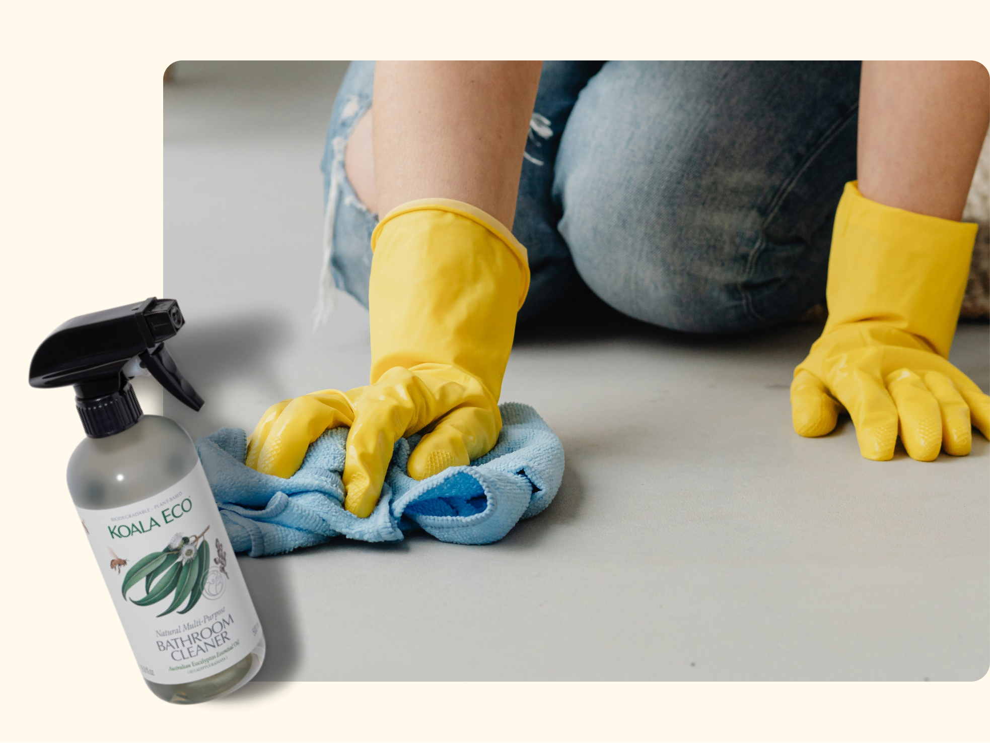 Person wearing yellow rubber gloves kneels on the floor, cleaning with a blue cloth. A spray bottle of Koala Eco Natural Bathroom Cleaner is shown in the foreground.