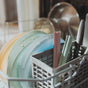 A close-up of Esembly Baby Reusable Silicone Sipper Straws with Storage Pouch, 4-pack, shown with pastel plates in a gray dishwasher rack. The clean, neatly arranged straws offer an eco-friendly sipping solution using upcycled materials.