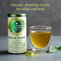 A tin of The Republic of Tea Organic SuperGreen Detox Green Tea sits next to a clear cup of green tea, a tea bag, and matcha powder. Text above reads: Organic, cleansing tea for the mind and body.