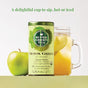 A tin of The Republic of Tea’s Organic SuperGreen Detox Green Tea, featuring matcha and chlorella, sits beside a mason jar of iced tea with lemon and a green apple. Text above reads, A delightful cup to sip, hot or iced.