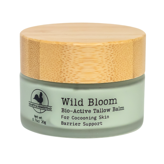 A small green jar with a wooden lid labeled Hearth and Homestead Tallow Face Cream - Anti-Aging delivers cocooning skin and barrier support. Packed with bio-active ingredients, this tallow face cream deeply nourishes while helping to protect against signs of aging. The logo features a house and rooster silhouette. Net weight: 0.7oz/20g.