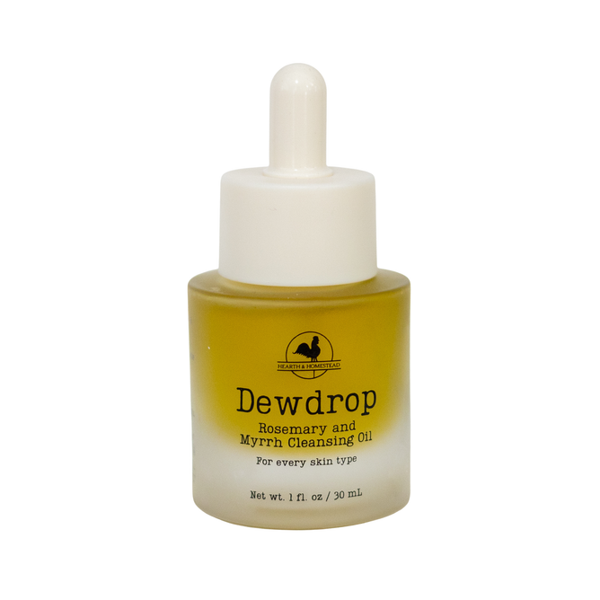 A small glass bottle of Hearth and Homestead Dewdrop Cleansing Oil, featuring a dropper cap and filled with yellowish oil. Formulated with nourishing oils, this cleansing oil suits every skin type and makes an excellent makeup remover. Net weight: 1 fl oz (30 mL).