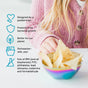 A child in a pink sweater holds the Ahimsa Smart Snacking Bowl with tortilla chips. Beside it, icons and text show its features: pediatrician-designed, antibacterial, eco-friendly, dishwasher-safe, and a plastic alternative.