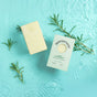 A Sunniemade Moisturizing Hand & Body Bar Soap – Very Rosemary and its box rest on a light blue watery surface with fresh rosemary sprigs, showcasing the invigorating essence of rosemary soap and the calming benefits of natural body care.