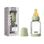 A BIBS Glass Baby Bottle with Natural Rubber Nipple Complete Set, featuring a green cap, measurement markings, and anti-colic design, is shown next to its packaging with product details and the BIBS logo.