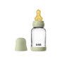 The BIBS Glass Baby Bottle with Natural Rubber Nipple Complete Set features a clear bottle with measurements, a green cap and base, and a yellow nipple with a heart design. The cap is shown next to the bottle on a light gray background.