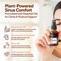 A woman holds a bottle of Marie Originals Sinus Congestion Relief Spray, featuring plant-powered relief with peppermint, wintergreen, clove essential oils, olive oil, and yellow sweet clover for clarity and post nasal drip support.