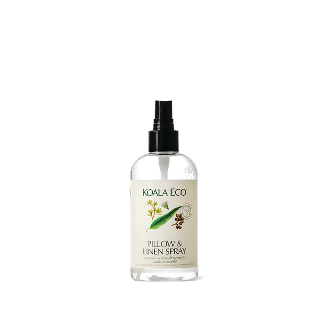 A clear spray bottle labeled "Koala Eco Pillow & Linen Spray" with a black nozzle, featuring botanical illustrations and green accents, is set against a white background—an elegant eucalyptus pillow spray from Koala Eco.