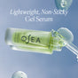 A clear bottle of OSEA Hyaluronic Acid Sea Serum is shown with “Lightweight, Non-Sticky Gel Serum” above it, surrounded by drops of gel on a light blue background.