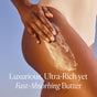 A person applies OSEA's Undaria Algae™ Body Butter to their upper thigh, wearing a light swimsuit against a clear blue sky. Text: Luxurious, ultra-rich, yet fast-absorbing body butter.