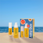 Two yellow OSEA Juicy Duo Lip + Body Oil bottles and a matching gift box sit on sand, with the ocean and sky behind. The packaging highlights hyaluronic acid-infused formulas for plump lips and glowing skin, evoking a summery beach vibe.