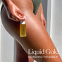 A person holds the OSEA Golden Glow Body Duo Gift Set against their glowy, hydrated thigh. Text reads: Liquid Gold, fast-absorbing + non-greasy for lasting moisture. They wear a green textured swimsuit.