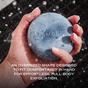 A hand grips the large, round, blue Charcoal Exfoliating Cleanser Bar from Ember Wellness, with water droplets splashing to showcase full-body exfoliation. Infused with natural pumice and activated charcoal, this oversized bar features a comfortable shape for effortless cleansing.