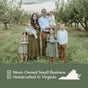 A family of seven in matching earth-toned outfits stands in an orchard. Text reads: Hearth and Homestead Whipped Tallow Balm—Mom-Owned Small Business, handcrafted in Virginia with grass-fed tallow, plus state outline and checkmarks.