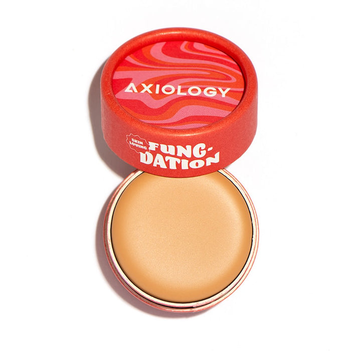 A close-up of a container featuring Axiology's Fungdation - Mushroom Foundation, designed to deliver moisture and a flawless finish.