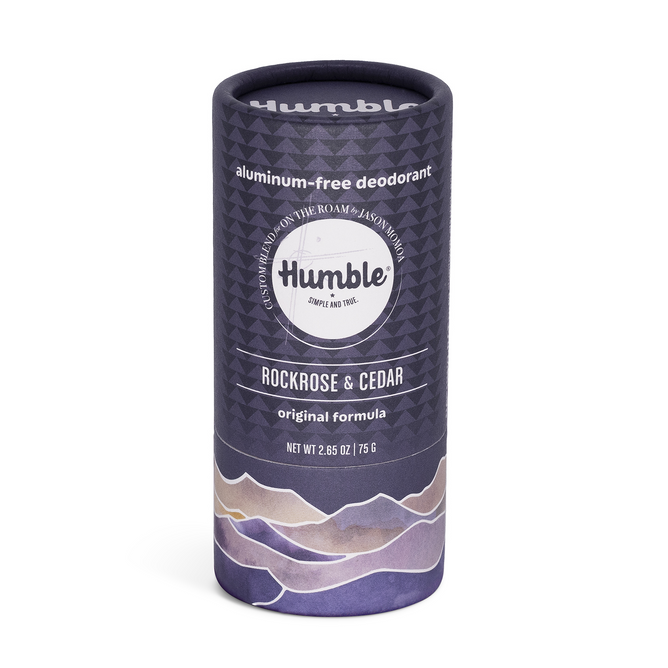 A cylindrical tube of Humble Brands Deodorant - Aluminum Free in Rockrose & Cedar, with a purple mountain design and text featuring its natural, cruelty-free formula and earth-friendly packaging.