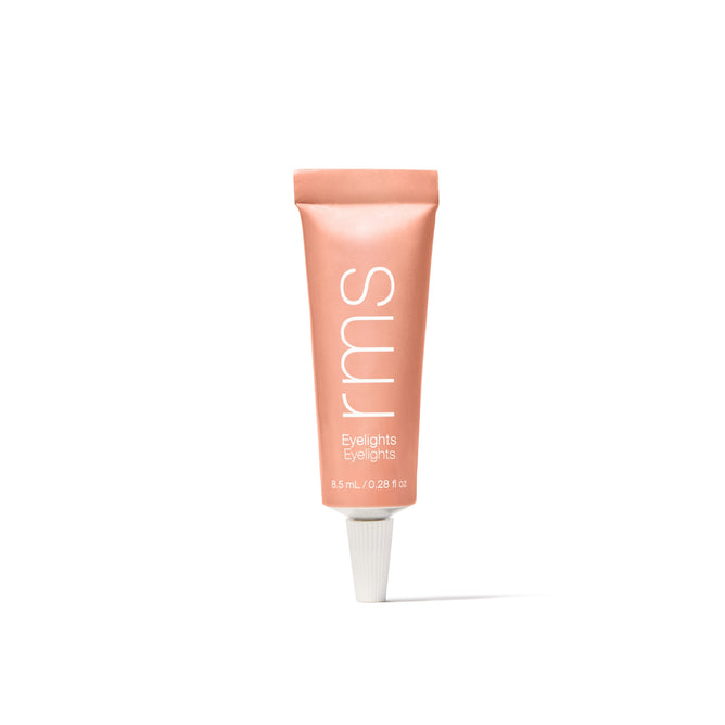 A peach-colored tube of RMS Beauty Eyelights Cream Eyeshadow stands upright on a white background with a white screw cap. The 8.5 ml (0.28 fl oz) cream eyeshadow is infused with organic green tea for a nourishing touch.