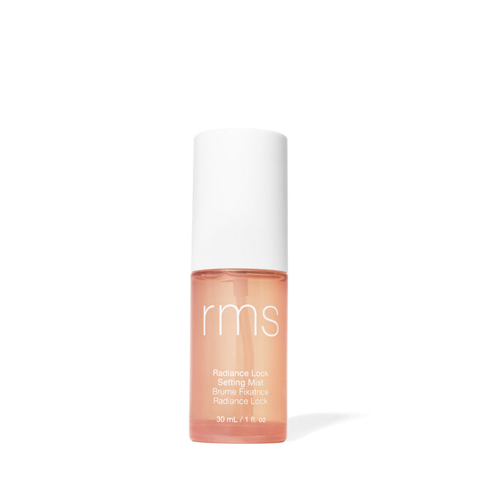 A small, clear bottle of RMS Beauty Radiance Lock Setting Mist with a white cap and light orange liquid, alcohol-free and radiance-enhancing, is shown against a plain white background.