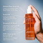 A hand holds a clear amber bottle of RMS Beauty Kakadu Beauty Body Oil, a fast-absorbing blend featuring Kakadu plum seed oil, buriti oil, and botanical and adaptogenic extracts.