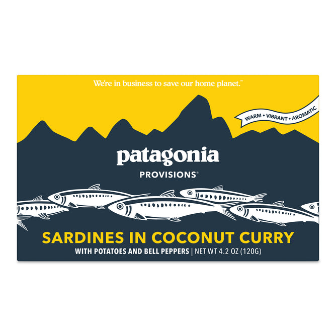 A rectangular package of Patagonia Provisions Sardines Coconut Curry features fish illustrations, a mountain design, and product details on a yellow and navy background.