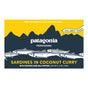A rectangular package of Patagonia Provisions Sardines Coconut Curry features fish illustrations, a mountain design, and product details on a yellow and navy background.