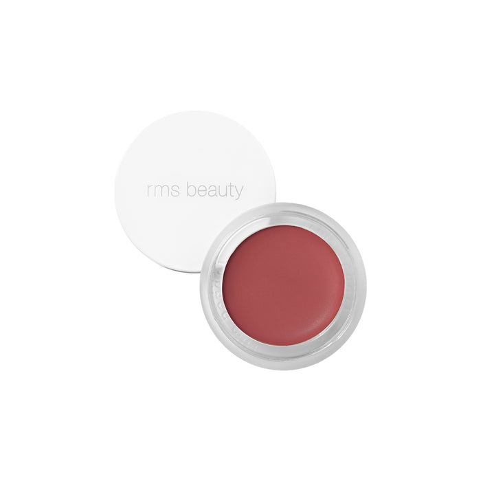 A round, open container of RMS Beauty Lip2cheek moisturizing cream blush in a muted rose shade, with a white lid set to the side. This natural formula is enriched with wildcrafted buriti oil for added nourishment.