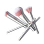 The RMS Beauty Skin2Skin Powder Blush Brush features soft white and pink bristles with a silver handle—perfect for a natural, airbrushed look. Shown here arranged in a scattered pattern on a white background.