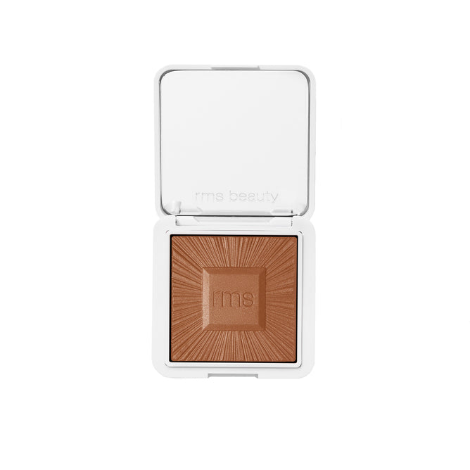 RMS Beauty’s ReDimension Hydra Bronzer is a compact, talc-free bronzer with a sunburst pattern and RMS logo embossed on the powder, housed in a white square refillable compact with an open lid.