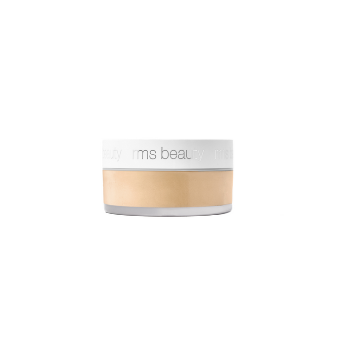A small, round container of RMS Beauty’s Hydra Setting Powder features a clear base, white lid, and light beige powder inside. The talc-free, skincare-infused loose powder has the brand name rms beauty printed in light gray on the lid.