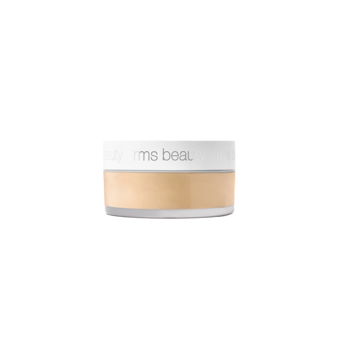 A small, round container of RMS Beauty’s Hydra Setting Powder features a clear base, white lid, and light beige powder inside. The talc-free, skincare-infused loose powder has the brand name rms beauty printed in light gray on the lid.