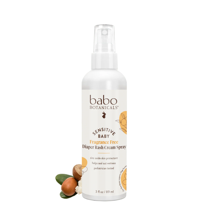 A 3 fl oz white spray bottle of Babo Botanicals Sensitive Baby Diaper Rash Cream Spray - Fragrance-Free, shown alongside illustrations of shea nuts and green leaves.