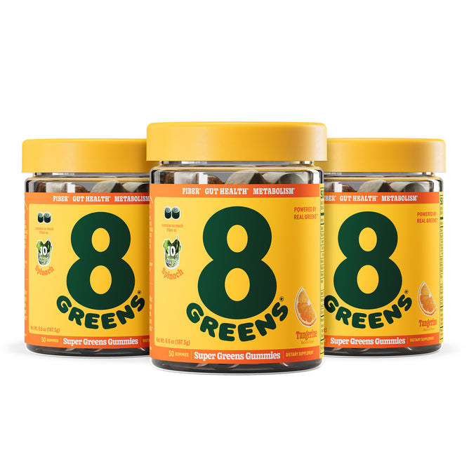 Three jars of 8Greens Super Greens Gummies - Fiber (Multi-Packs) are lined up, each sporting a yellow label with bold dark green text. They aid fiber, gut health, and metabolism, featuring tangelo flavor highlighted by vivid fruit illustrations.