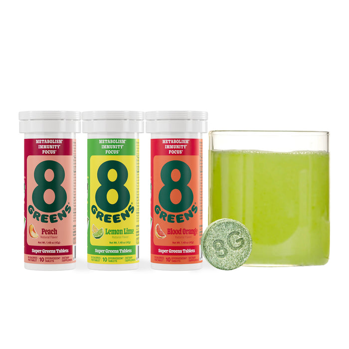 Three tubes of 8Greens Super Greens Tablet - Variety Pack in peach, lemon-lime, and blood orange are next to a glass of green liquid. An 8G tablet suggests their powerful immune-boosting blend.