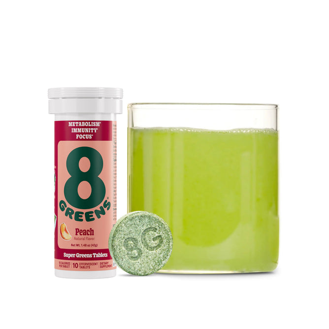 A container of 8Greens Super Greens Tablet - Peach is next to a glass of green liquid, with a single 8G tablet ready to boost metabolism and immunity, symbolizing wellness in each sip.