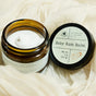 A jar of Hearth and Homestead Baby Bum Balm for natural baby skin care sits open on cream fabric, its brown jar with a white label highlighting soothing, protective ingredients. The lid rests beside the jar.