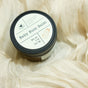 A round container of Hearth and Homestead Baby Bum Balm, a natural baby skin care essential, sits on cream fabric. The 2 oz (56.7g) white label features a sweet baby illustration—perfect for soothing diaper rash.