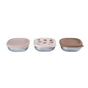 Three shallow, round BEABA Stainless Steel Bowls with Lid Set are lined up. The left bowl is topped with a solid beige silicone lid, the center features a white silicone lid with holes—perfect for weaning food storage—and the right has a solid brown lid. Each microwave-safe lid includes a convenient tab for easy opening.