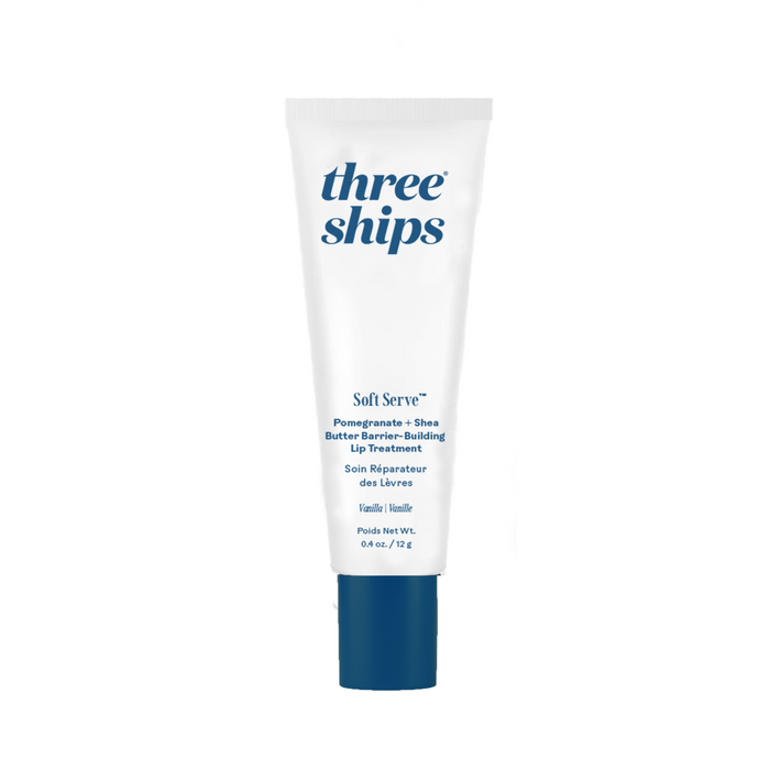 A white tube of Three Ships SoftServe™ Barrier-Building Lip Treatment with a dark blue cap and blue text highlights its vanilla flavor and pomegranate bio-active complex for lasting hydration.
