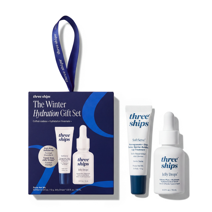 The Winter Hydration Gift Set, a holiday duo box with a hanging ribbon, containing a lip treatment tube and a dropper bottle of hydrating serum, with the same two items placed next to the box.
