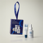 The Winter Hydration Gift Set in a box with a hanging ribbon, including a squeeze tube of lip treatment and a dropper bottle of hydrating serum.