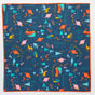 Bee’s Wrap Reusable Gift Wrap: a square organic cotton cloth with a dark blue background, colorful nature-inspired Vermont artist design (trees, leaves, arrows, deer, cars, foxes), plus orange stitching—perfect for eco-friendly gift wrapping.