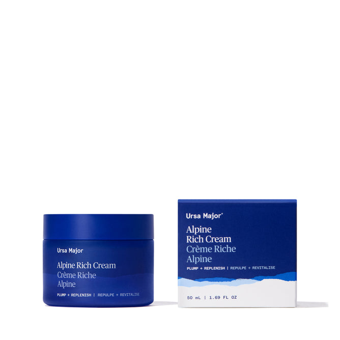 A blue Ursa Major Alpine Rich Cream jar and matching box sit side by side on a white background, both featuring minimalist mountain graphics and white text that emphasize skin barrier support.