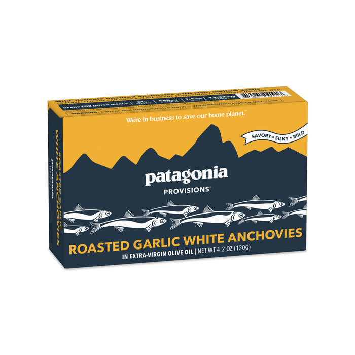 A box of Patagonia Provisions White Anchovies Roasted Garlic. The yellow and blue packaging features fish illustrations and text describing the product as savory, silky, and mild.