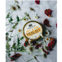 A tin of Anima Mundi's HEAL-ALL Arnica Relief Balm, Nourish, Soothe + Repair rests on white fabric among dried rose petals and small white flowers, offering an inviting touch of soothing skin hydration.