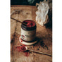 A jar of Anima Mundi’s MANGOSTEEN HIBISCUS Beauty Tonic rests on wood, filled with red mangosteen and hibiscus powder. A spoon atop the jar and another with the blend are shown, crystals glimmering in the background.